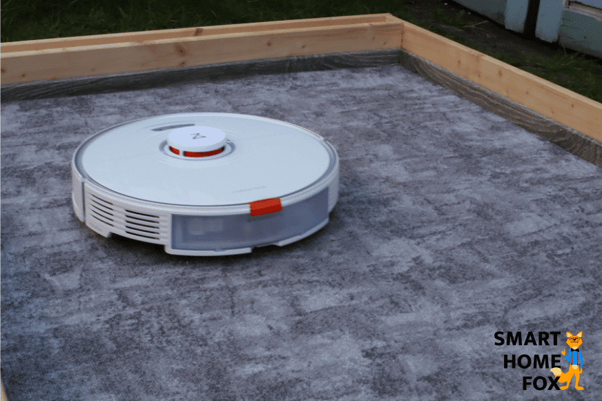 Roborock S7 пылесосит песок на ковре с низким ворсом.